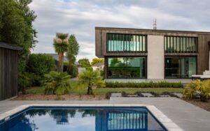 Modern home with timber cladding and outdoor lounge on a polished concrete patio with step detail.